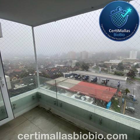 Malla de seguridad en balcón con baranda de vidrio, día lluvioso