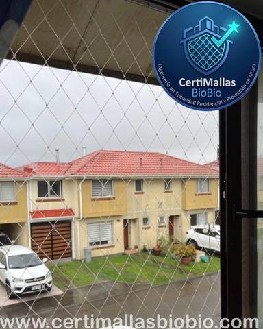 Malla de seguridad instalada en ventana, vista a casas vecinas