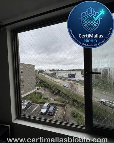 Malla de seguridad instalada en balcón con vista nocturna a la ciudad