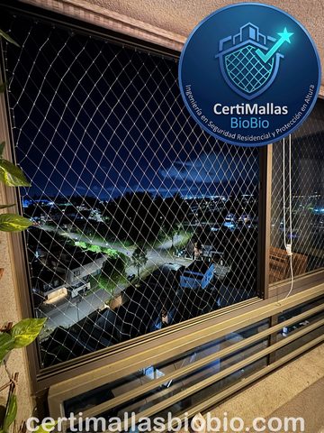 Malla de seguridad instalada en ventana con vista nocturna a la ciudad