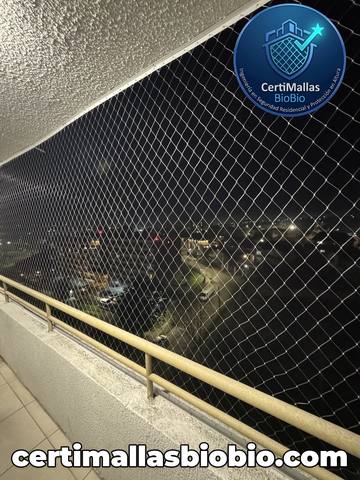 Malla de seguridad instalada en balcón con vista nocturna a la ciudad